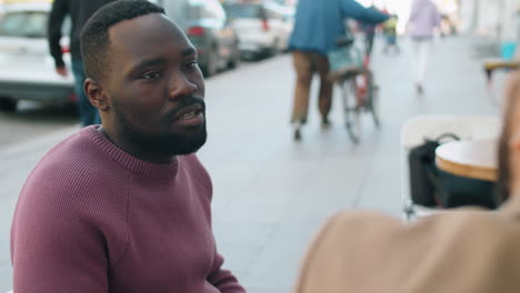 Hombre-Afroamericano-Hablando-Con-Un-Colega-En-Un-Café-Al-Aire-Libre